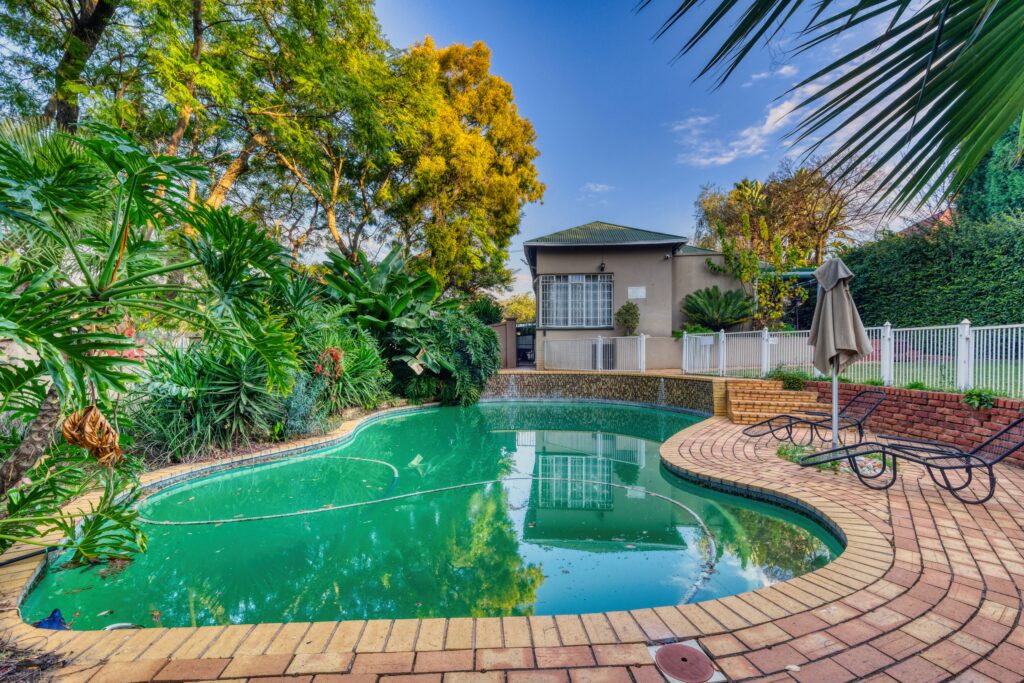 A tranquil backyard pool amidst lush greenery in Pretoria, South Africa.